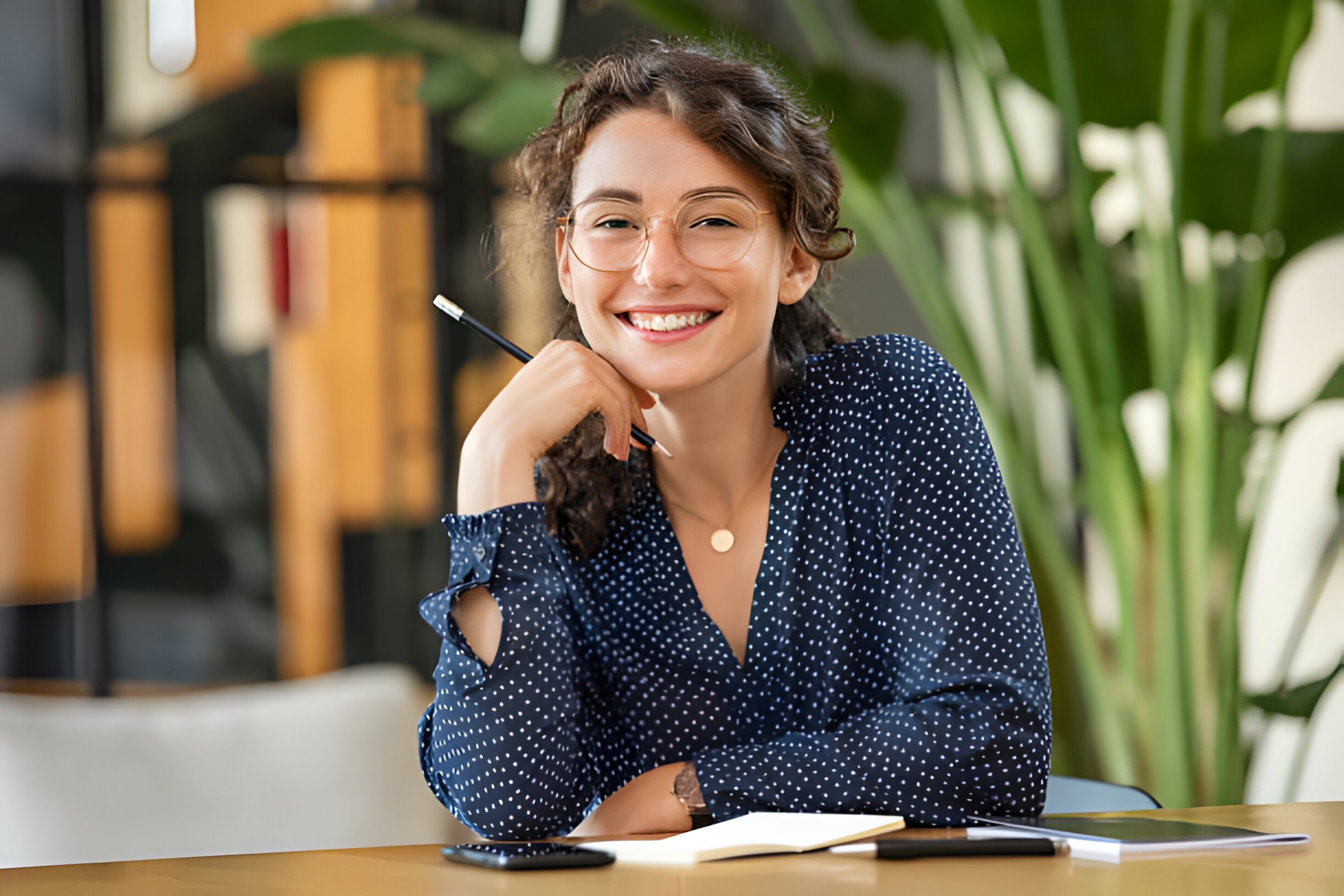a woman smiling with a pencil on her chin